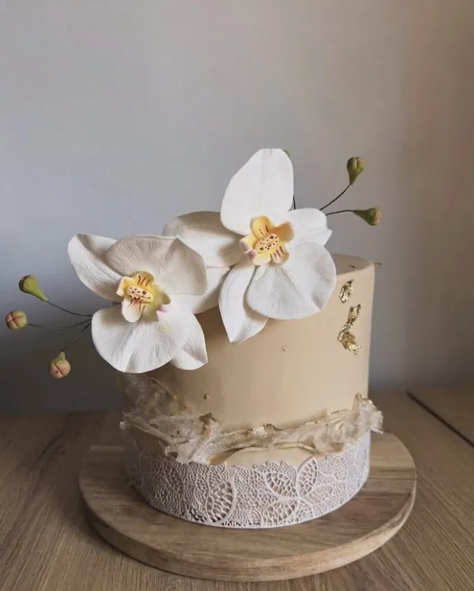 Gâteau élégant beige décoré d'orchidées blanches
